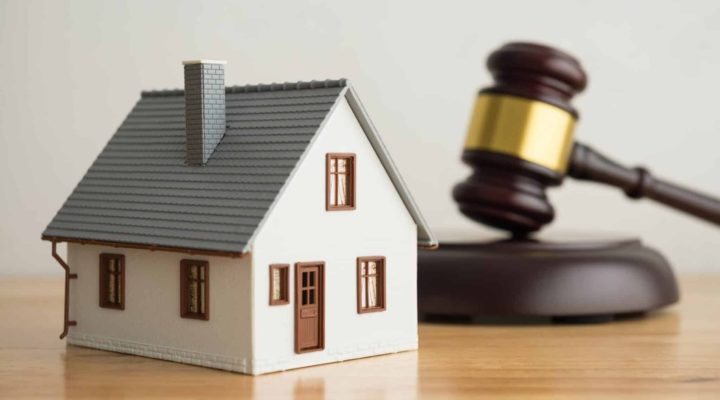 The image shows a beautiful two-story house with a gavel superimposed on it, symbolising divorce.