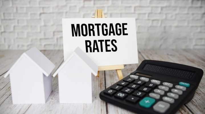 Mortgage Rates text message with calculator and house model on wooden background