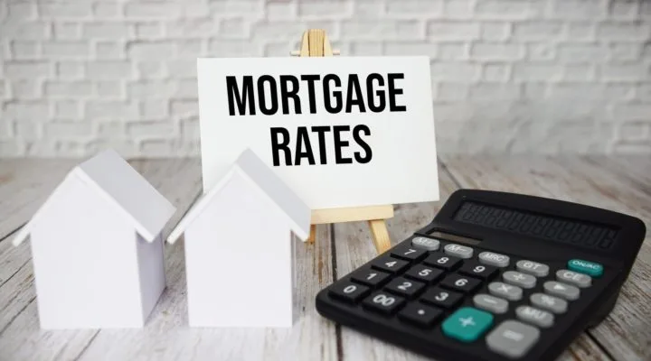 Mortgage Rates text message with calculator and house model on wooden background