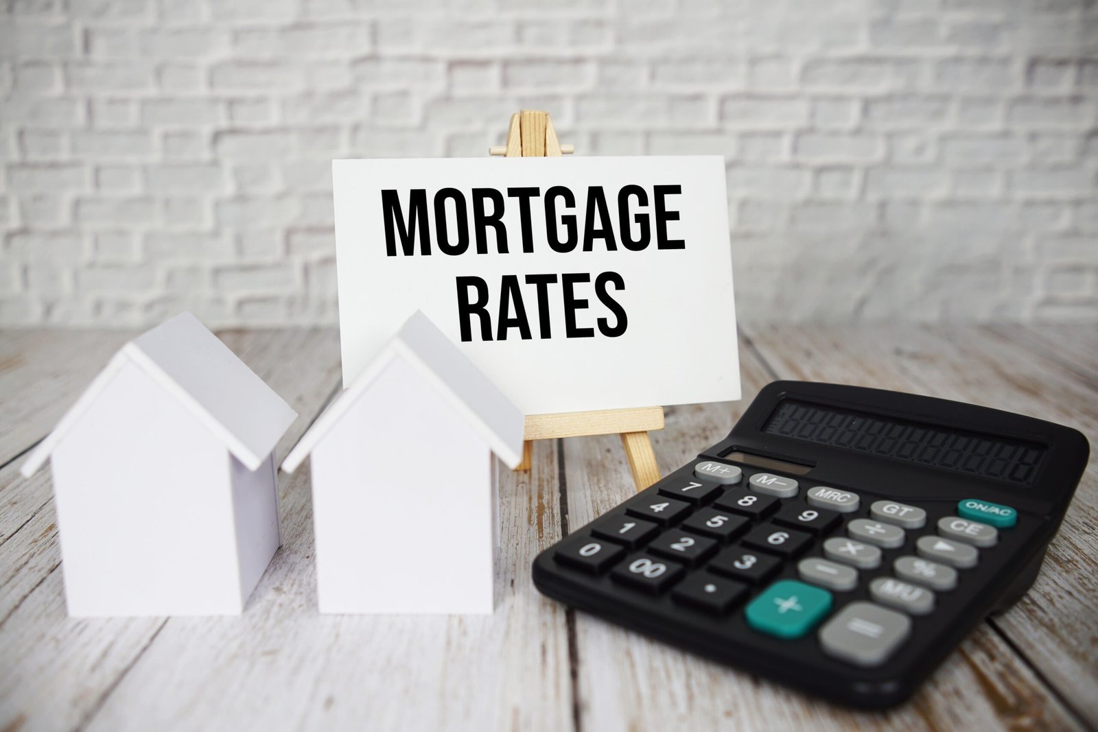 Mortgage Rates text message with calculator and house model on wooden background