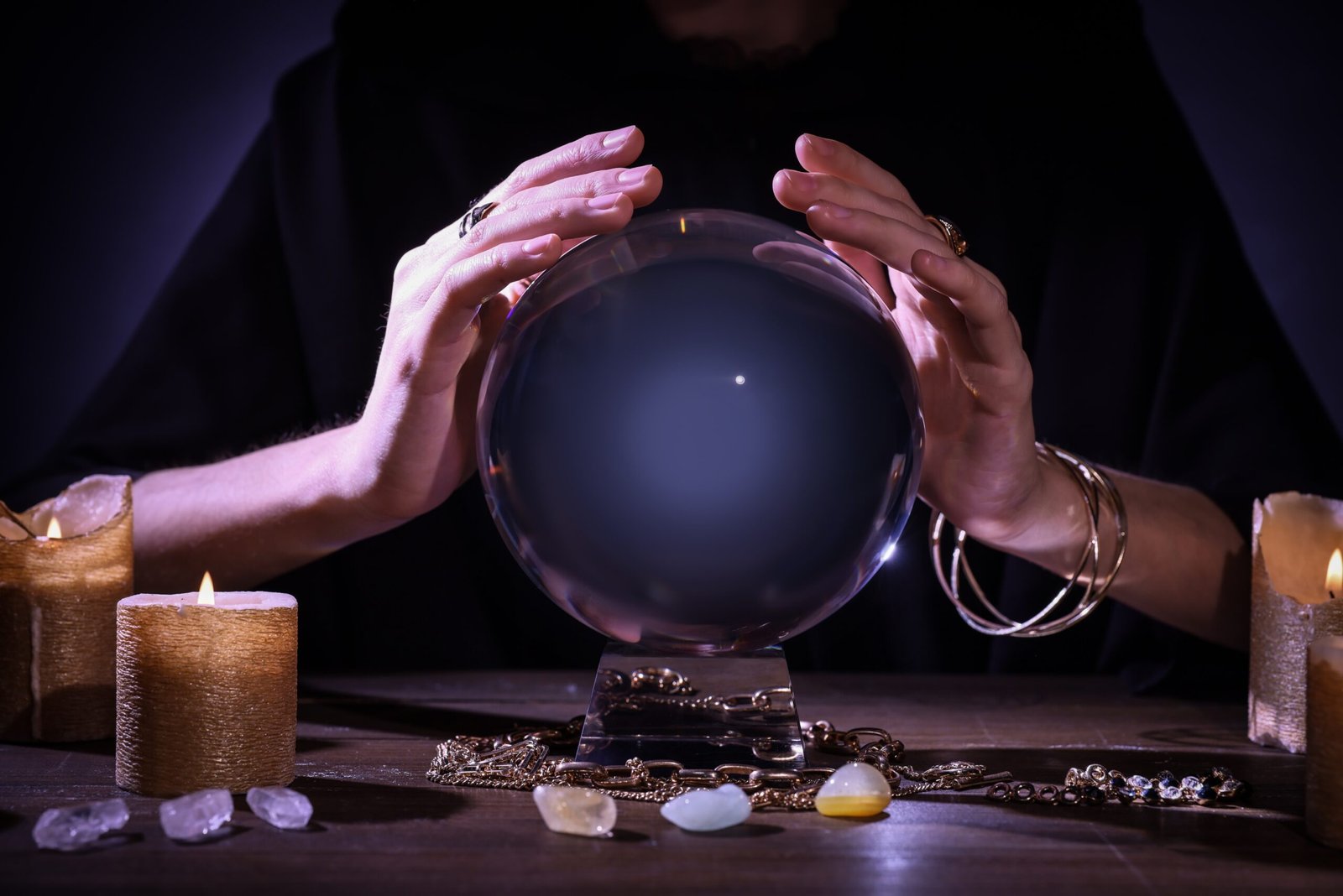 hands over a crystal ball with tarot cards on a table